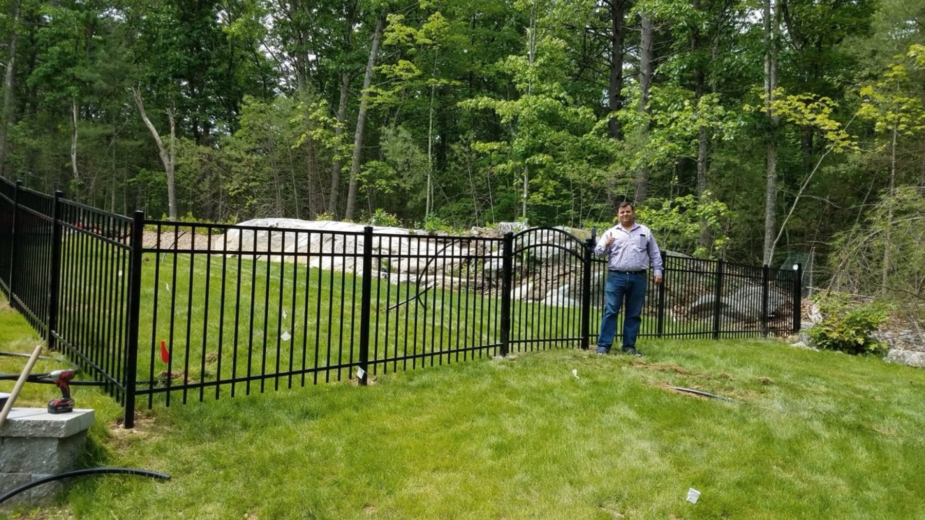 Black ornamental aluminium fence with an arched gate around a landscaped back lawn