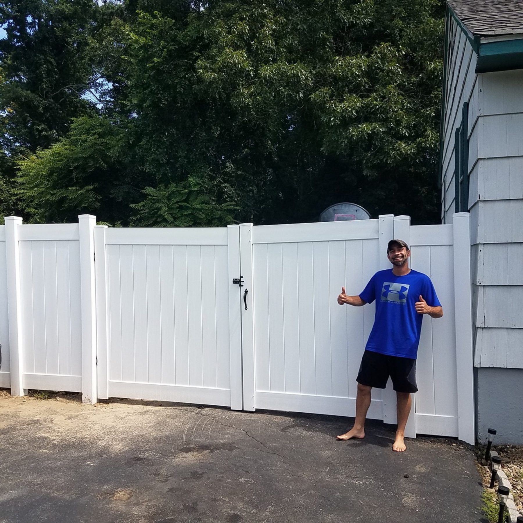 White vinyl privacy fence with a matching gate beside a residential driveway